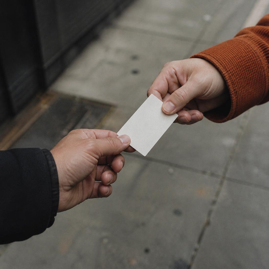 Close-up of two hands passing a blank printed card during a street-level brand interaction